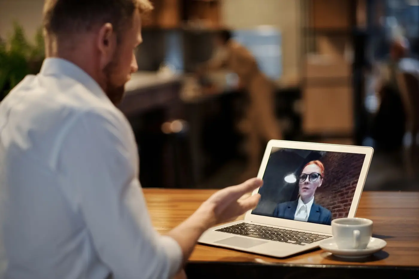 Un uomo seduto al tavolo parla in videochiamata con una consulente sullo schermo del portatile