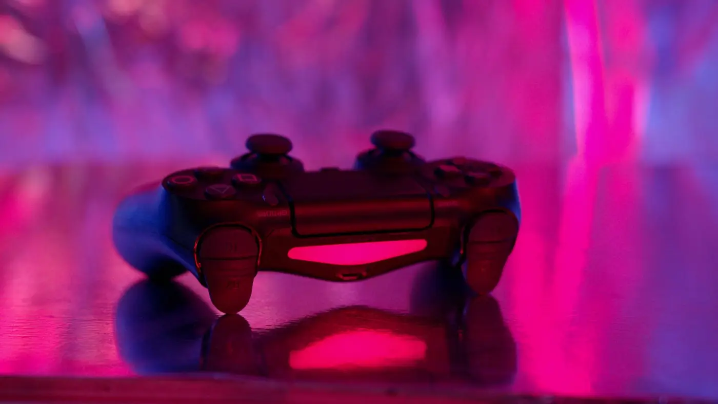 Un controller da gioco illuminato da luci al neon rosa e viola